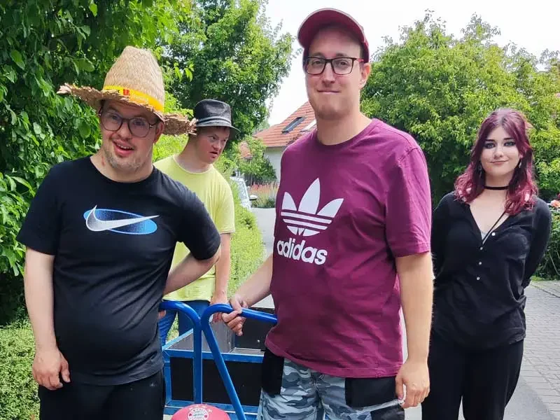 Bewohner und eine Kollegin aus dem Freiwilligendienst transportieren frisch gewaschene Wäsche zu den Häusern.